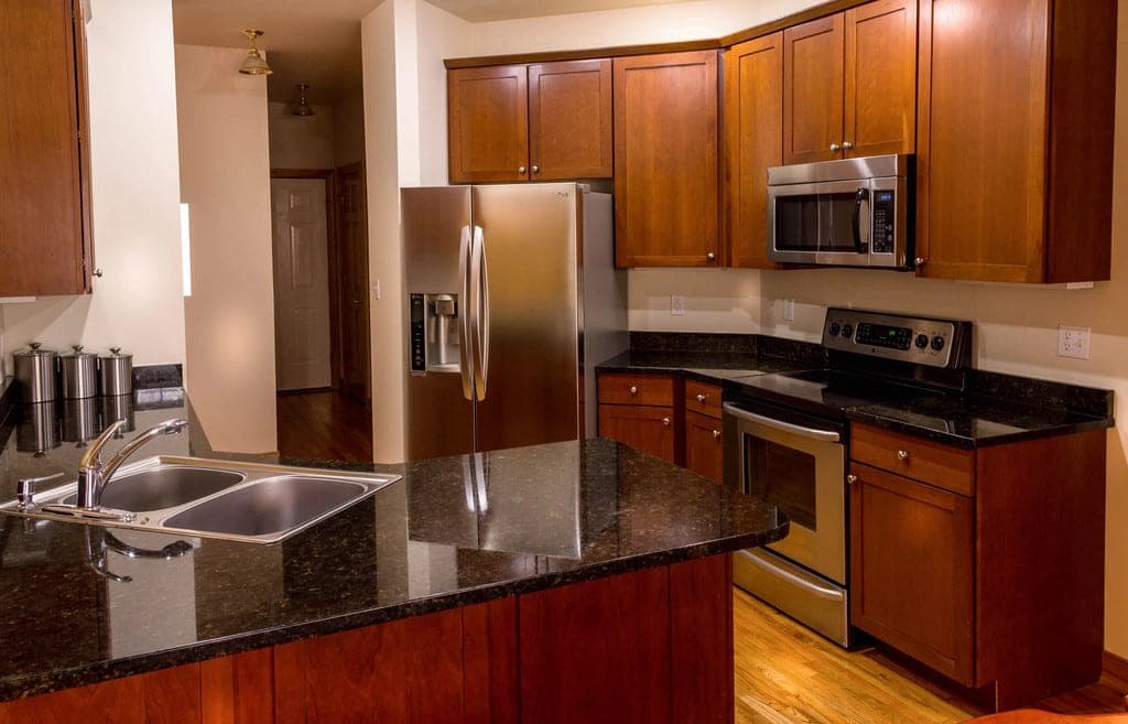 Cherry cabinets, granite countertops and stainless appliances in a finished residential kitchen.